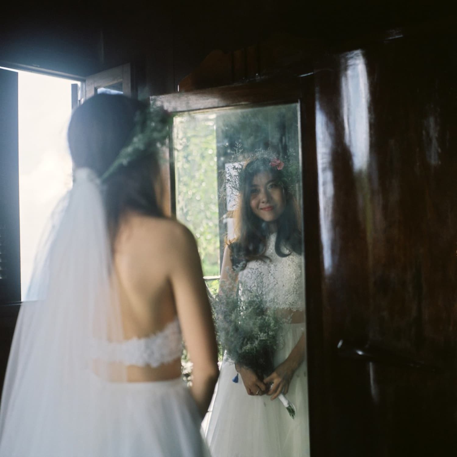 Bride reflected in an antique mirror in soft window light