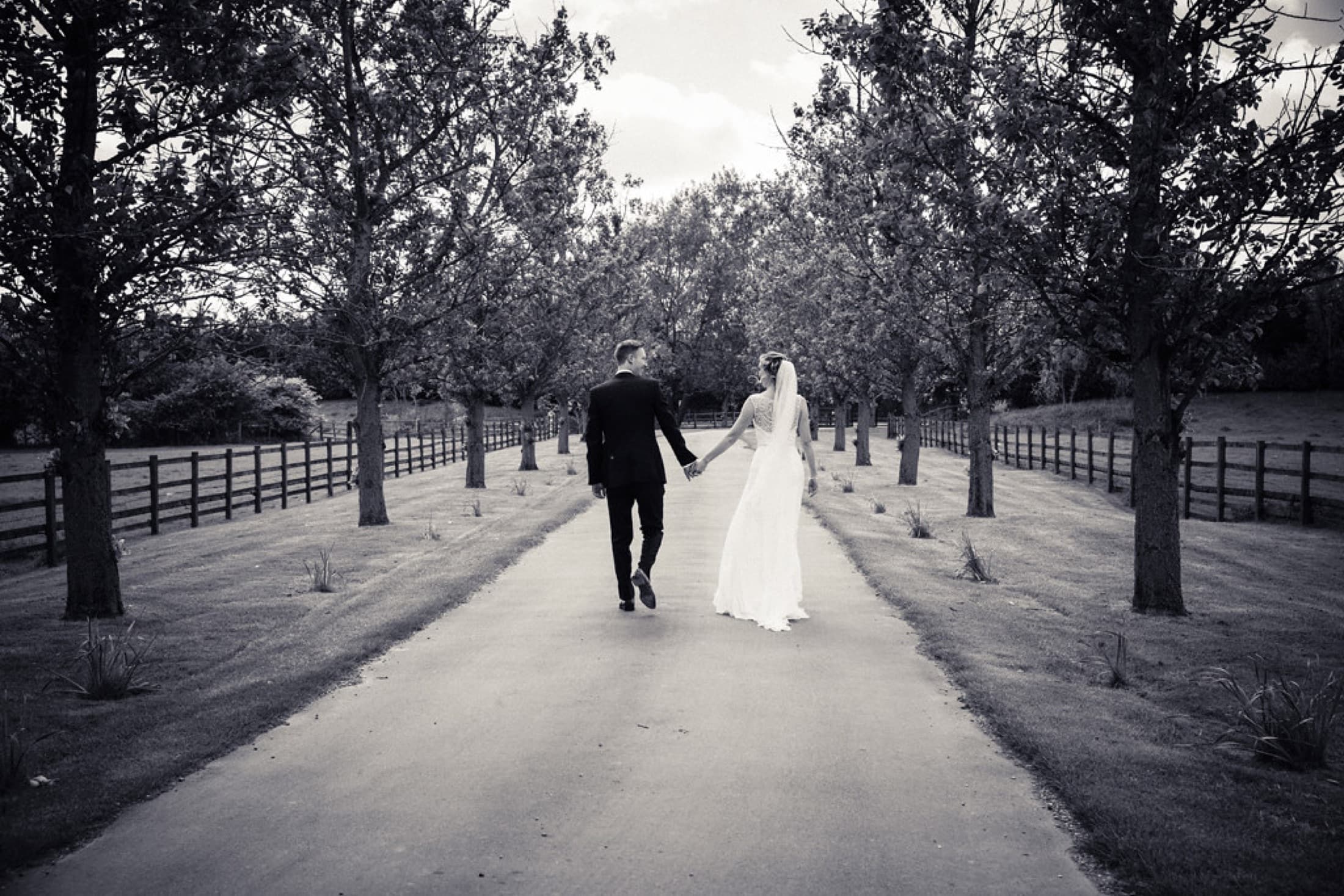 A couple walking a tree-lined avenue on their wedding day